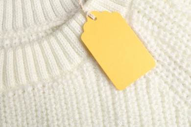 Photo of Cardboard tag on white knitted sweater, top view