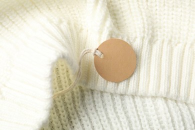 Photo of Cardboard tag on white knitted sweater, top view