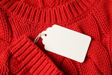 Photo of Cardboard tag on red knitted sweater, top view