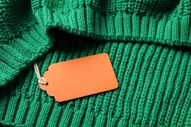 Photo of Cardboard tag on green knitted sweater, above view