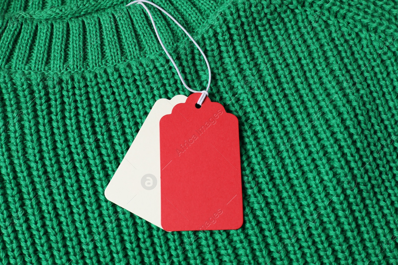 Cardboard tags on green knitted sweater, top view Photo of Cardboard tags on green knitted sweater, top view