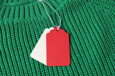 Photo of Cardboard tags on green knitted sweater, top view