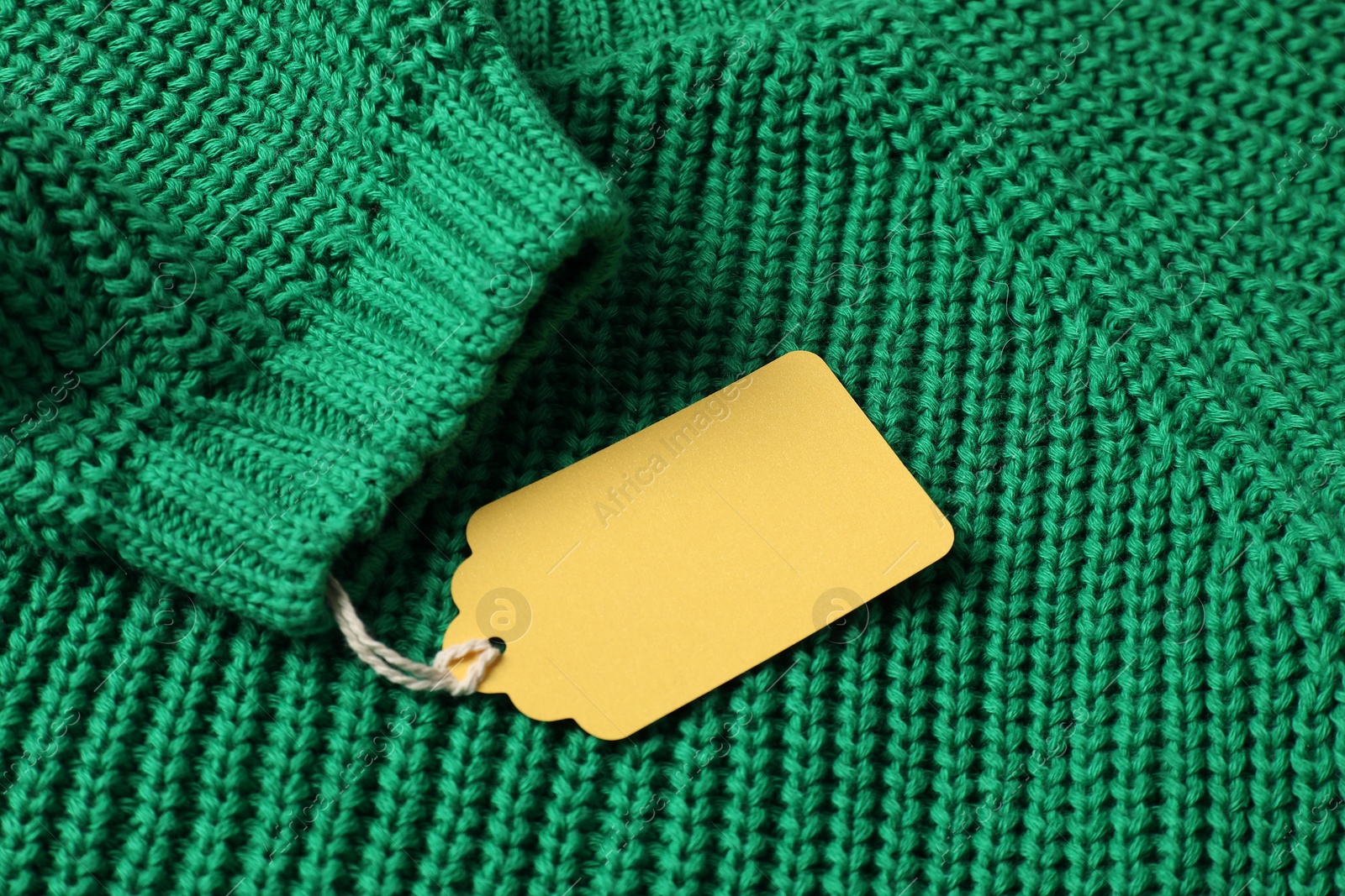 Cardboard tag on green knitted sweater, above view Photo of Cardboard tag on green knitted sweater, above view