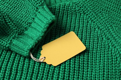 Photo of Cardboard tag on green knitted sweater, above view