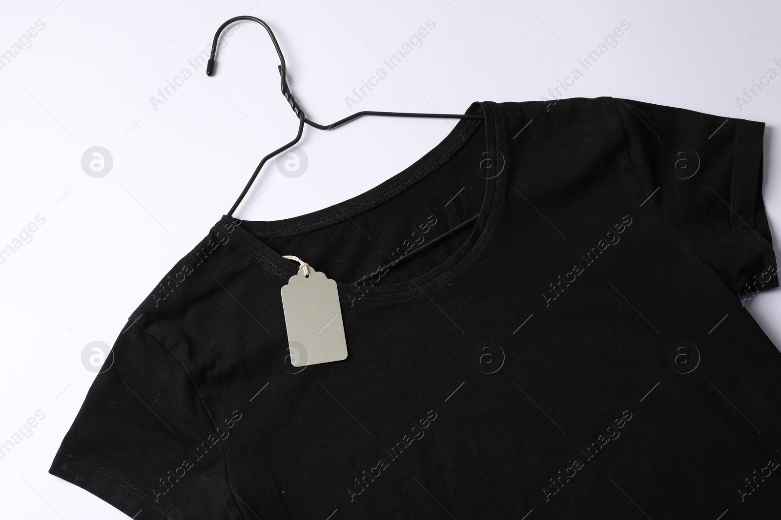 T-shirt with tag on white background, top view Photo of T-shirt with tag on white background, top view