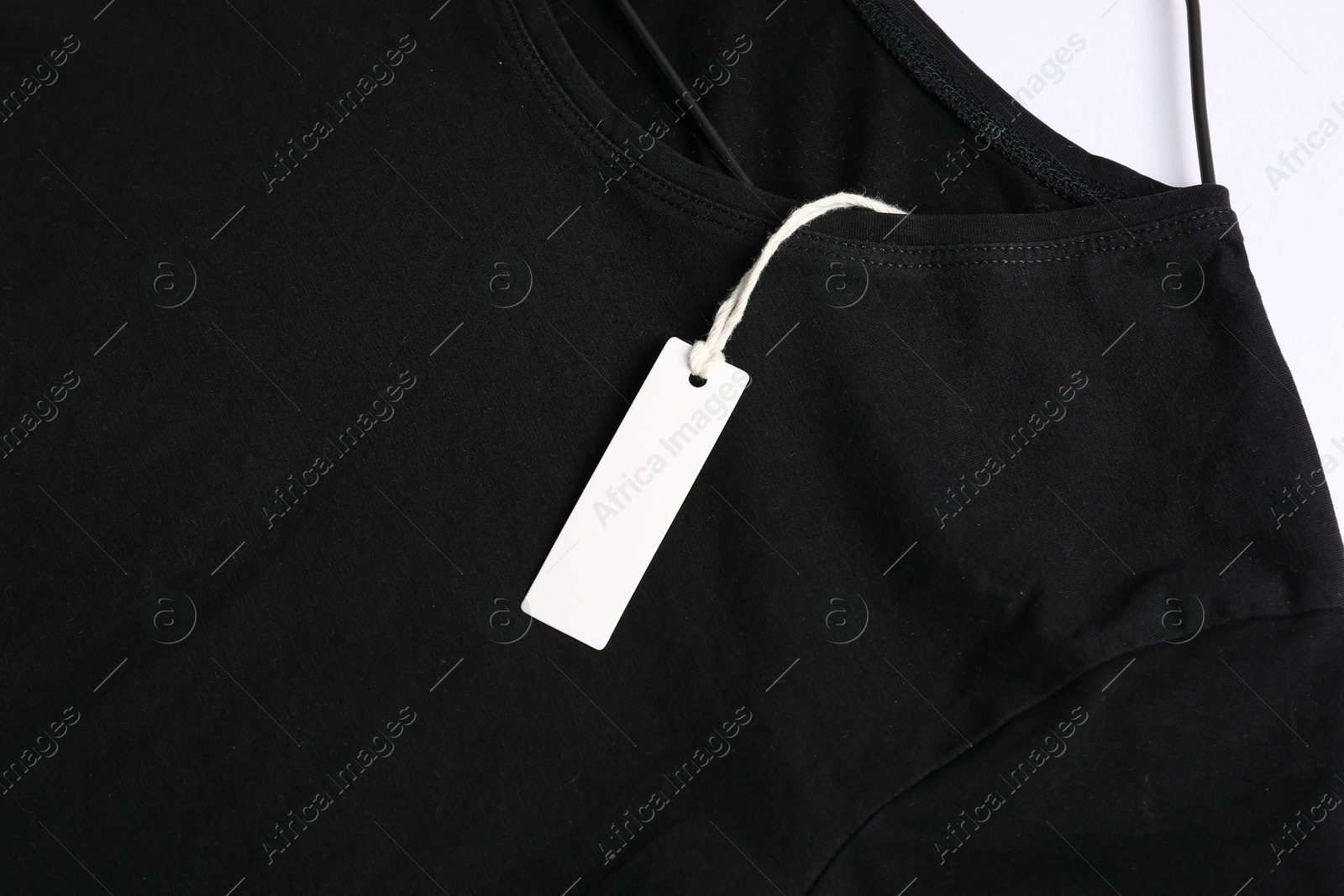 T-shirt with tag on white background, top view Photo of T-shirt with tag on white background, top view