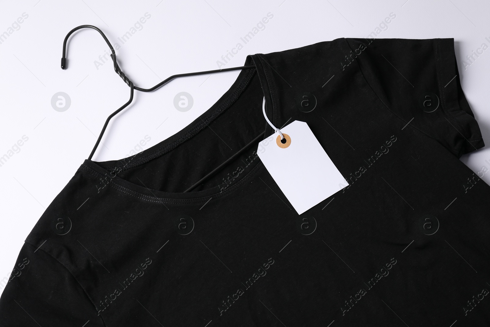 T-shirt with tag on white background, top view Photo of T-shirt with tag on white background, top view