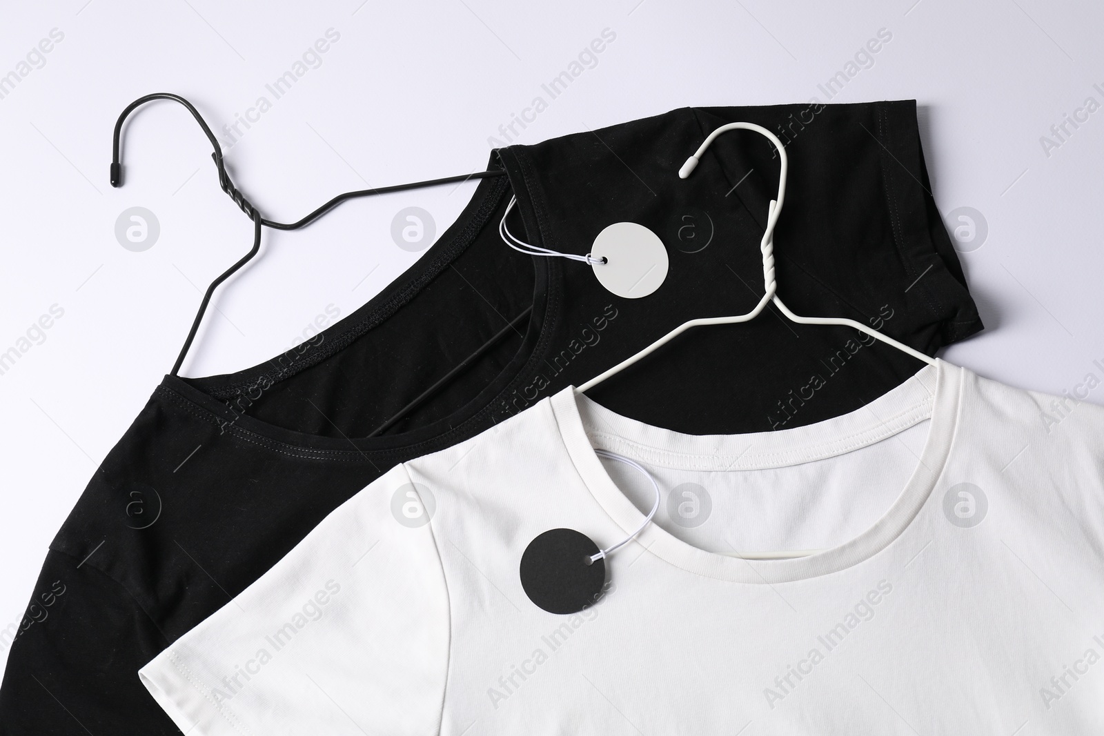 T-shirts with tags on white background, top view Photo of T-shirts with tags on white background, top view