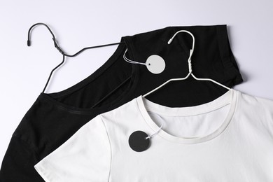 Photo of T-shirts with tags on white background, top view