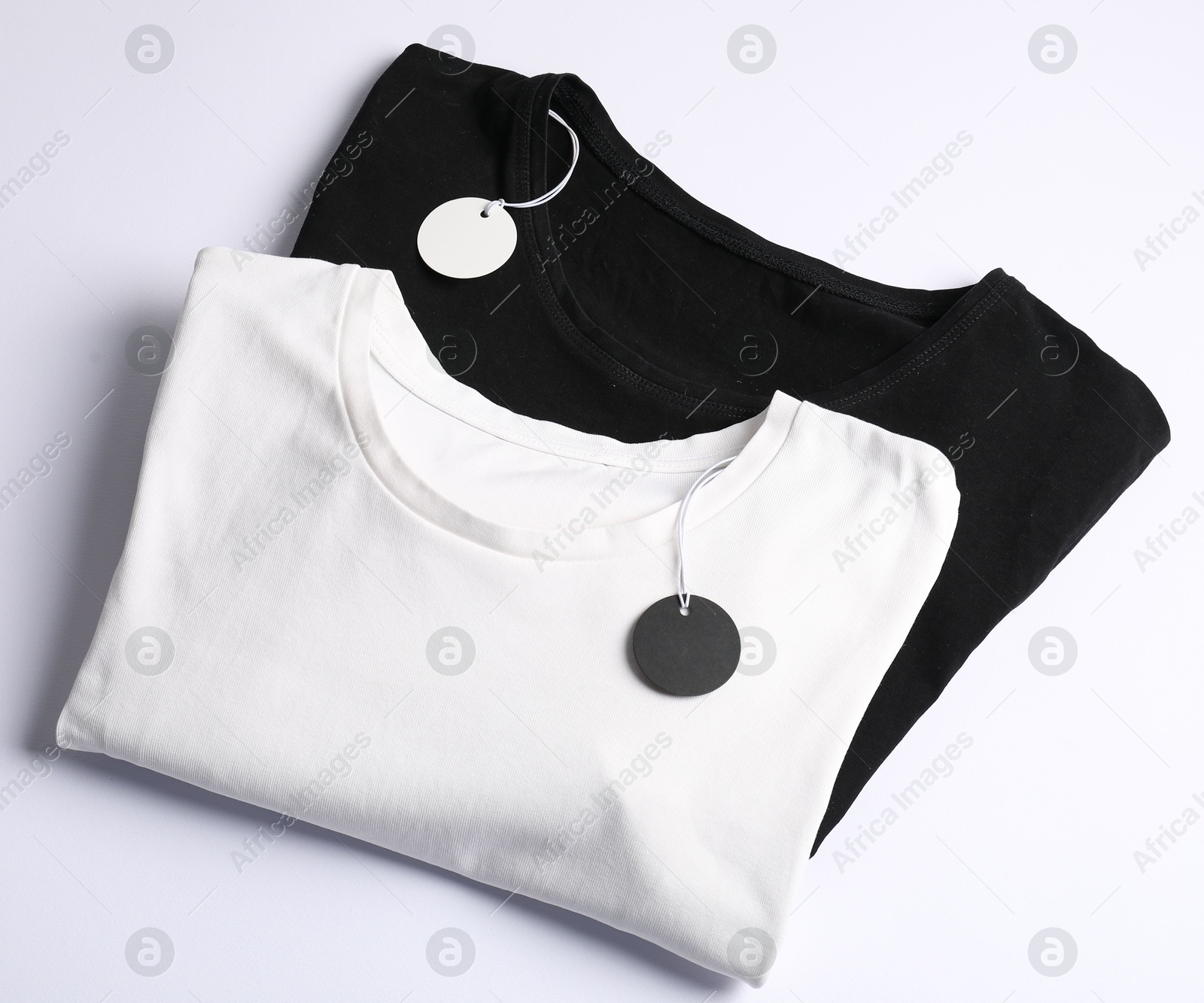 T-shirts with tags on white background, top view Photo of T-shirts with tags on white background, top view