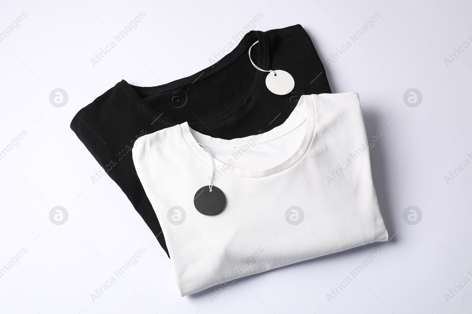 T-shirts with tags on white background, top view Photo of T-shirts with tags on white background, top view