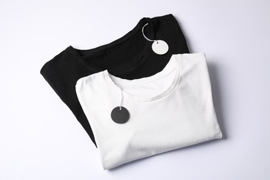 Photo of T-shirts with tags on white background, top view