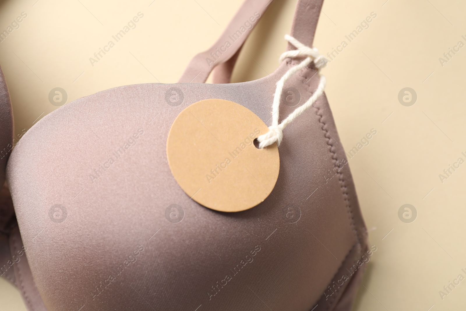 Bra with tag on beige background, above view Photo of Bra with tag on beige background, above view