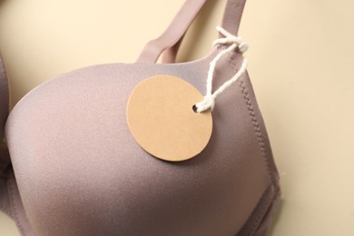 Photo of Bra with tag on beige background, above view
