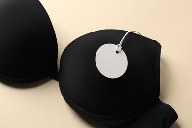 Photo of Black bra with tag on beige background, above view