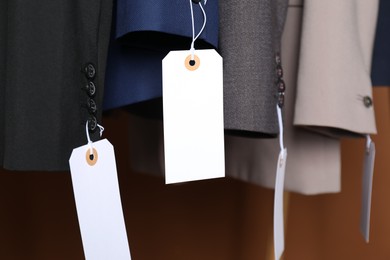 Photo of Different jackets with tags on brown background, closeup