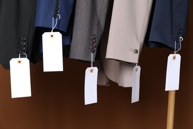 Photo of Different jackets with tags on brown background, closeup