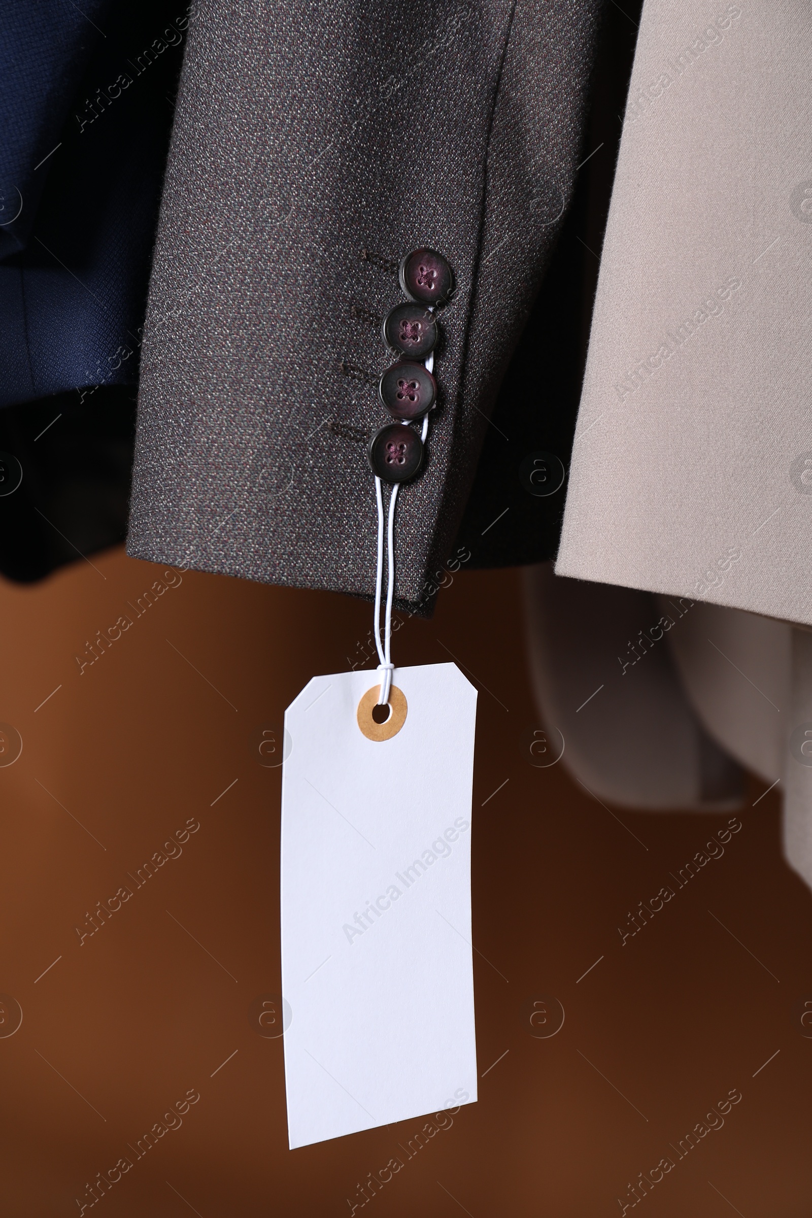 Different jackets with tags on brown background, closeup Photo of Different jackets with tags on brown background, closeup