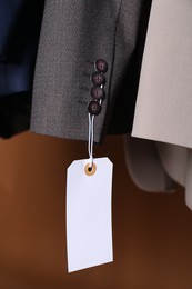 Photo of Different jackets with tags on brown background, closeup