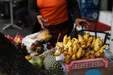 Photo of Woman selling different exotic fruits at market, closeup