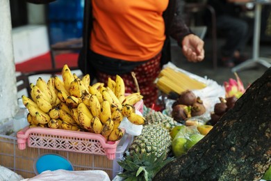 Photo of Woman selling different exotic fruits at market, closeup