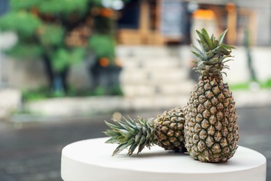 Photo of Fresh ripe pineapples on white table outdoors, space for text