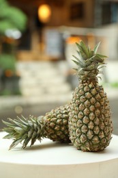 Photo of Fresh ripe pineapples on white table outdoors
