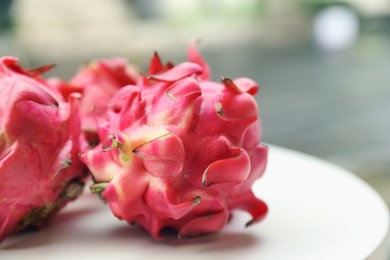 Photo of Delicious pitaya fruits on white table outdoors, closeup. Space for text
