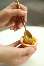 Photo of Woman eating passion fruit at table outdoors, closeup