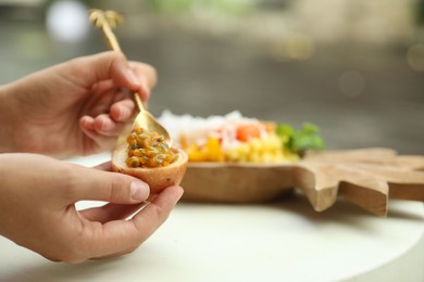 Photo of Woman eating passion fruit at table outdoors, closeup