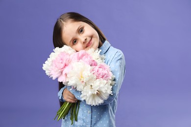 Photo of Cute little girl with bouquet of beautiful peonies on purple background
