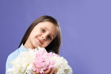 Photo of Cute little girl with bouquet of beautiful peonies on purple background, space for text