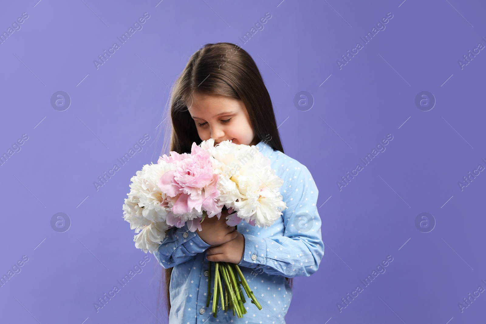Cute little girl with bouquet of beautiful peonies on purple background Photo of Cute little girl with bouquet of beautiful peonies on purple background