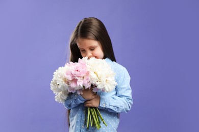 Photo of Cute little girl with bouquet of beautiful peonies on purple background