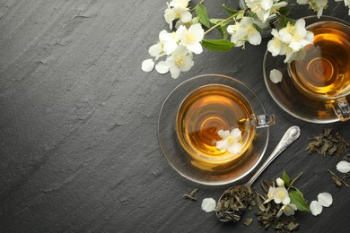 Photo of Aromatic jasmine tea, brew and flowers on grey table, flat lay. Space for text