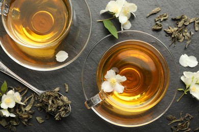 Photo of Aromatic jasmine tea, brew and flowers on grey table, flat lay
