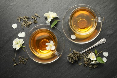 Photo of Aromatic jasmine tea, brew and flowers on grey table, flat lay