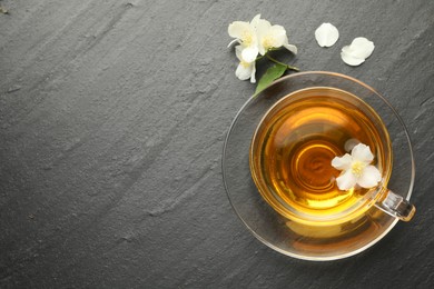 Photo of Aromatic jasmine tea and flowers on grey table, flat lay. Space for text