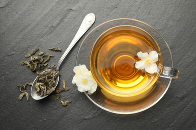 Photo of Aromatic jasmine tea, brew and flowers on grey table, flat lay