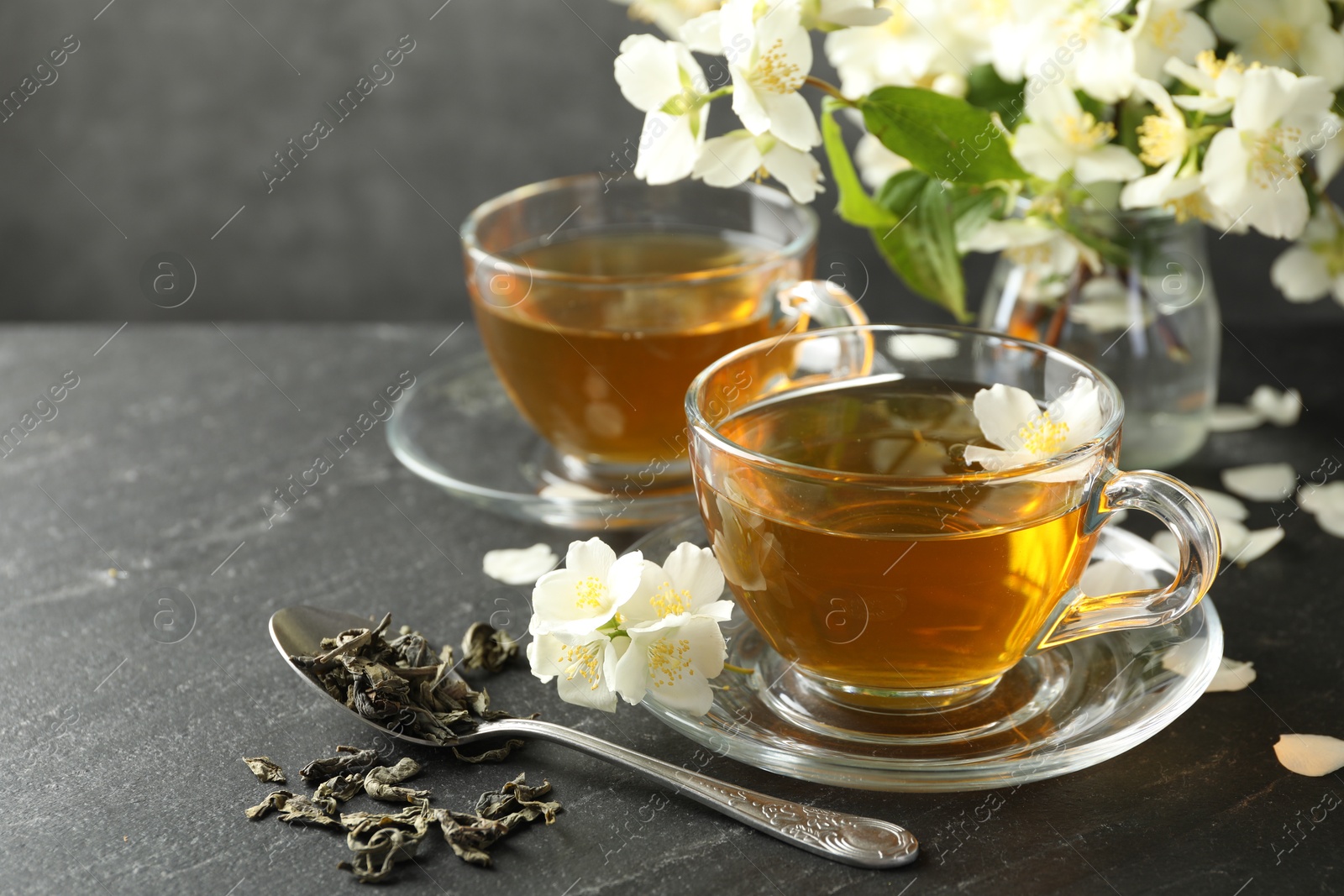 Aromatic jasmine tea, brew and flowers on grey table, closeup Photo of Aromatic jasmine tea, brew and flowers on grey table, closeup