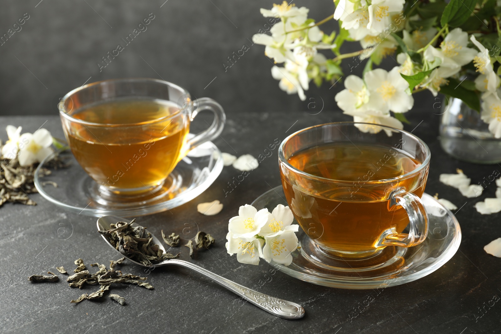 Aromatic jasmine tea, brew and flowers on grey table Photo of Aromatic jasmine tea, brew and flowers on grey table