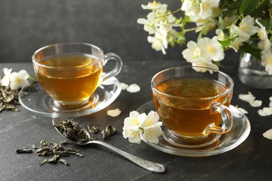 Photo of Aromatic jasmine tea, brew and flowers on grey table