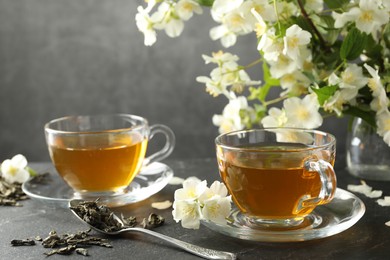 Photo of Aromatic jasmine tea, brew and flowers on grey table