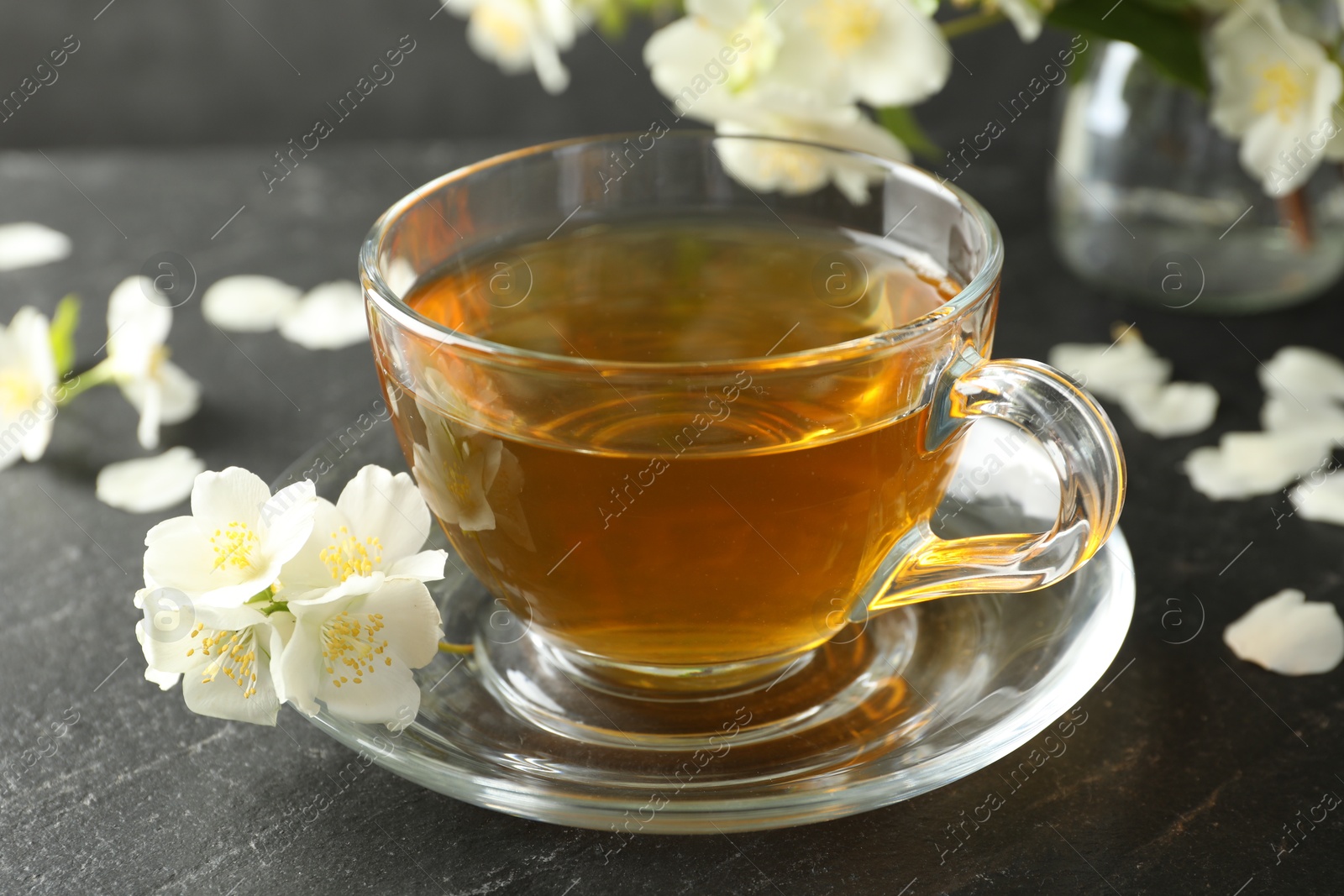 Aromatic jasmine tea and flowers on grey table, closeup Photo of Aromatic jasmine tea and flowers on grey table, closeup