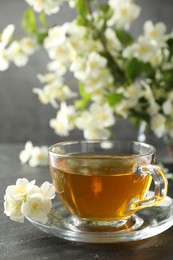 Photo of Aromatic jasmine tea and flowers on grey table