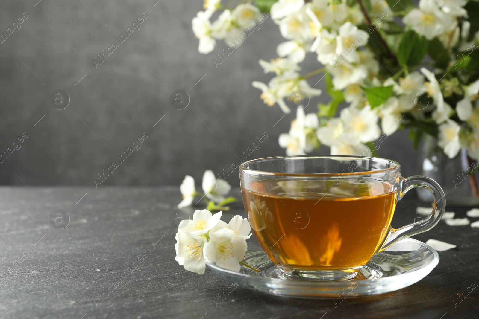Aromatic jasmine tea and flowers on grey table. Space for text Photo of Aromatic jasmine tea and flowers on grey table. Space for text