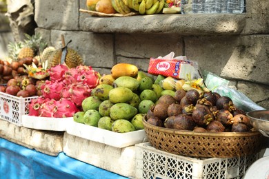 Photo of Bali, Indonesia - May 15, 2025: Fresh ripe fruits near stone building at market