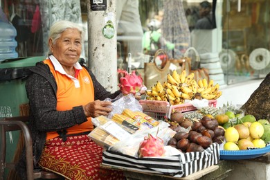 Photo of Bali, Indonesia - May 15, 2025: Senior woman selling different tropical fruits at market