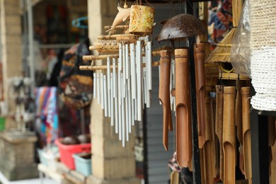 Photo of Different wind chimes in outdoor souvenir shop, closeup. Space for text