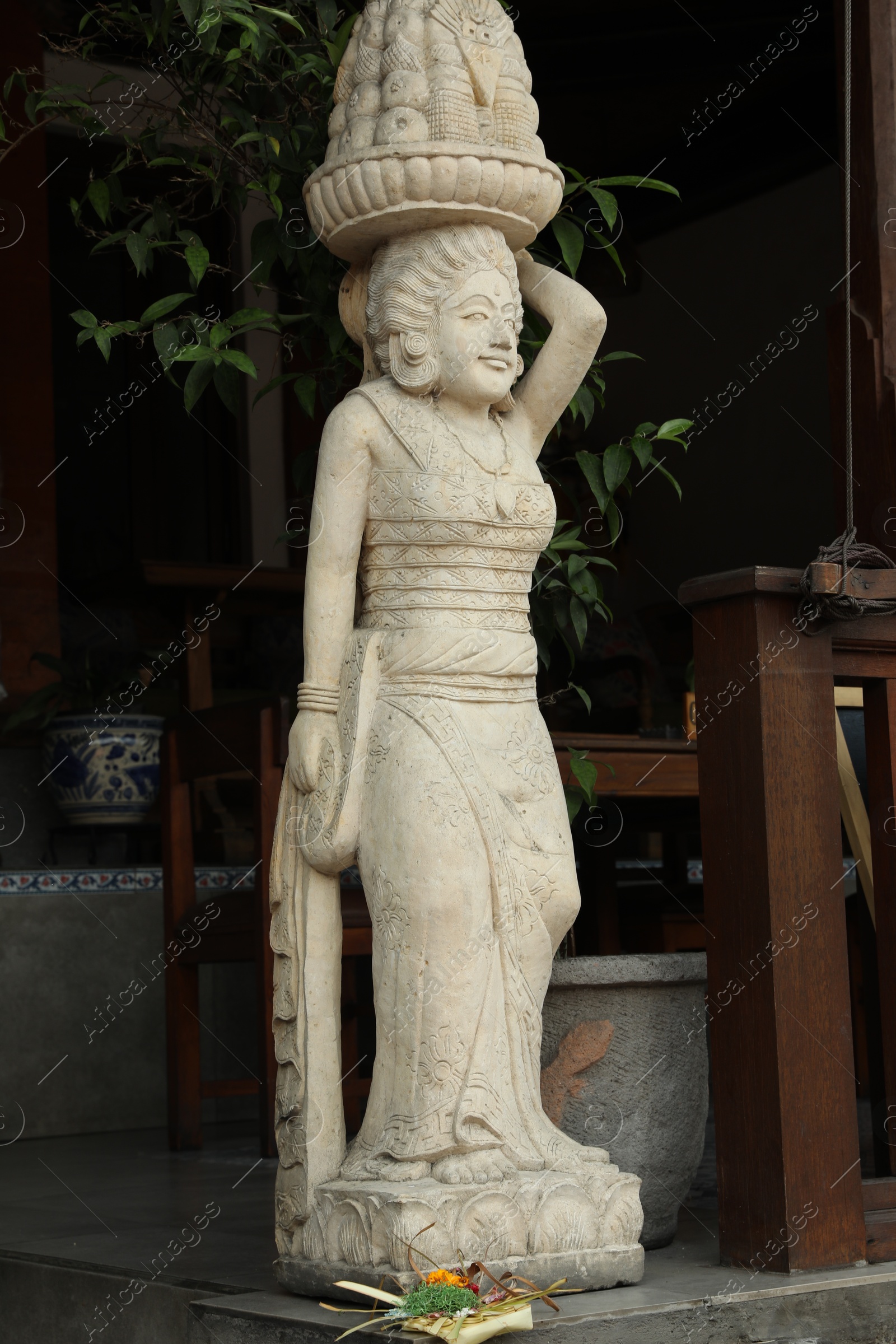 Bali, Indonesia - May 15, 2025: Beautiful ancient sculpture of woman with basket of fruits on city street Photo of Bali, Indonesia - May 15, 2025: Beautiful ancient sculpture of woman with basket of fruits on city street